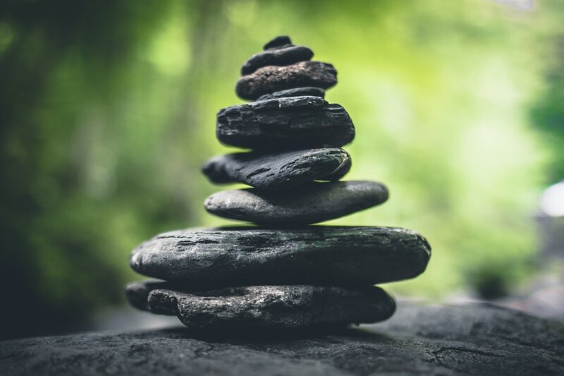 Black stacking stones balanced in layers on a grey surface, representing stacked pull requests