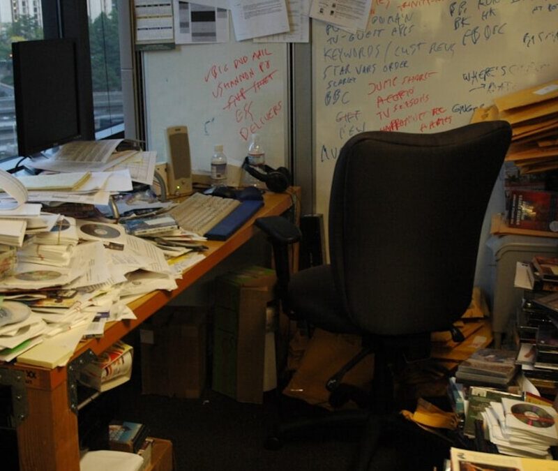 Office table covered with a pile of paper documents, representing intake backlog