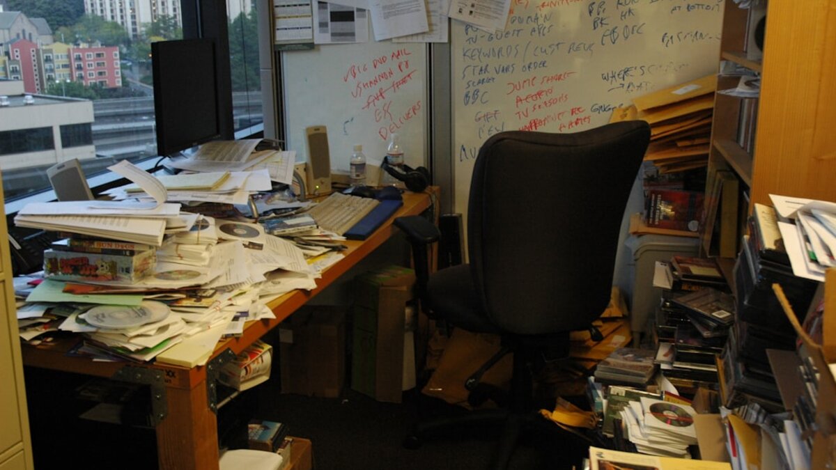 Office table covered with a pile of paper documents, representing intake backlog