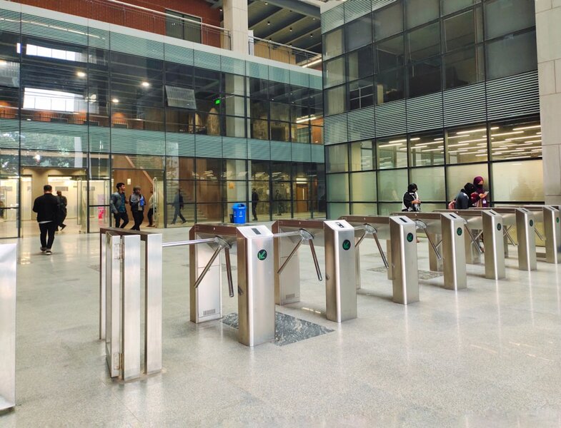 A row of security turnstiles in a modern office lobby