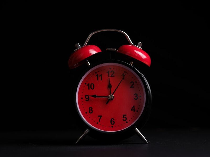 A red alarm clock on a black background