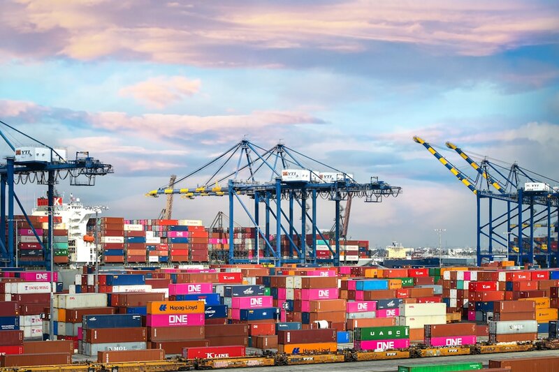 Stacked red and blue shipping containers at a port, representing model artefact distribution and registry ownership