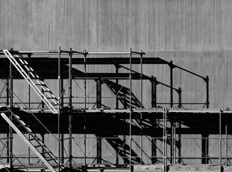 Scaffolding erected against a blank concrete wall, representing a structure built on supports somebody else owns