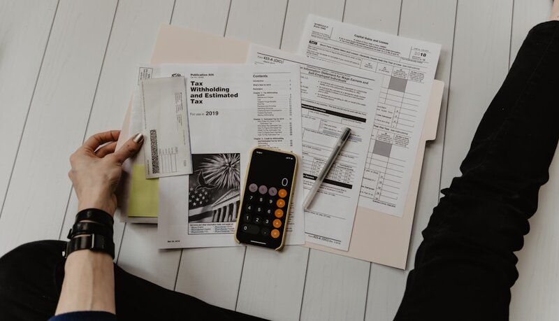 Calculator, pen and paperwork on a desk representing software project budgeting