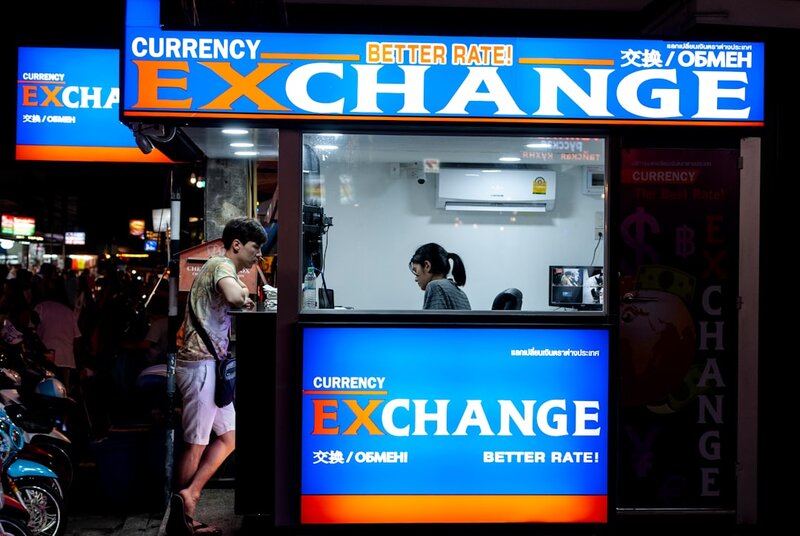 A currency exchange counter with rate boards, representing the secondary market in resold AI credits