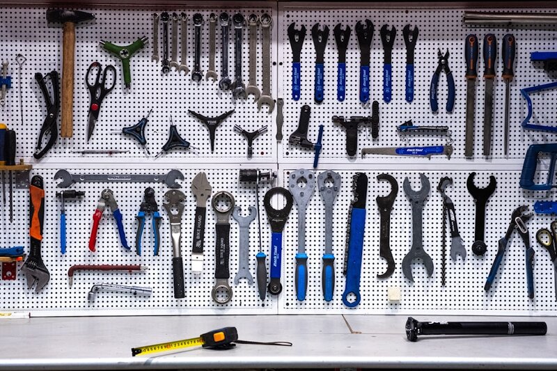 A wall of hand tools hanging on hooks in a workshop, most of them untouched
