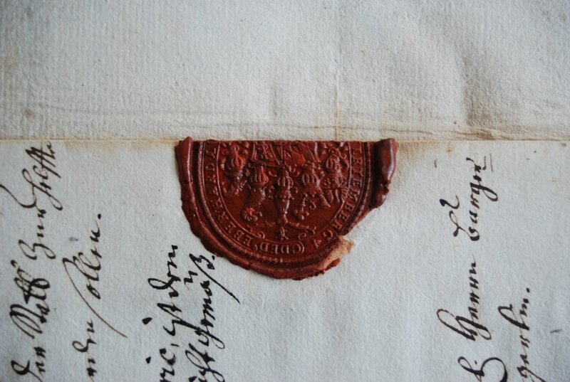 A red wax seal pressed onto an old handwritten document