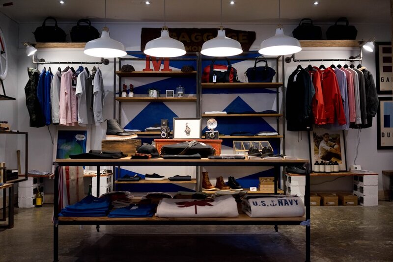 Interior of a small boutique with a single central table holding a carefully edited selection of clothing and shoes