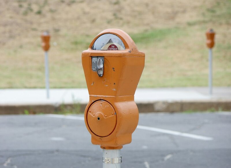 An orange parking meter showing TIME EXPIRED, two further meters standing behind it