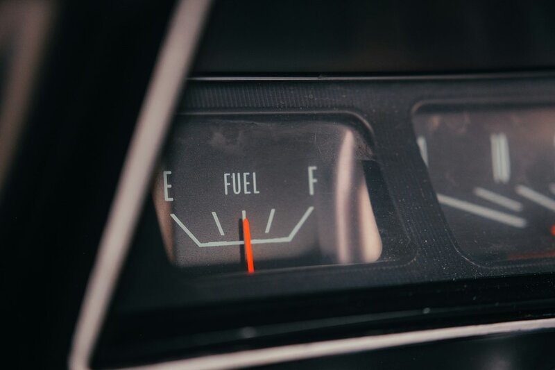 Close-up of a car gauge cluster, needle low, the fuel budget you only check when it runs out