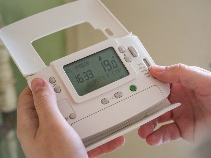 A person holding a programmable heating controller showing a temperature reading, representing a connected product whose data must be accessible to its user by default