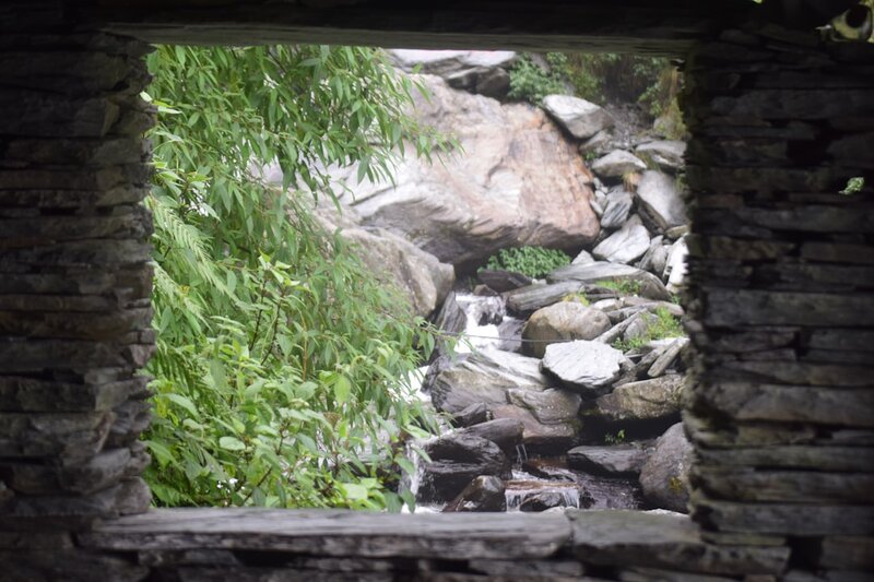 A stone window opening framing a waterfall cascading over rocks