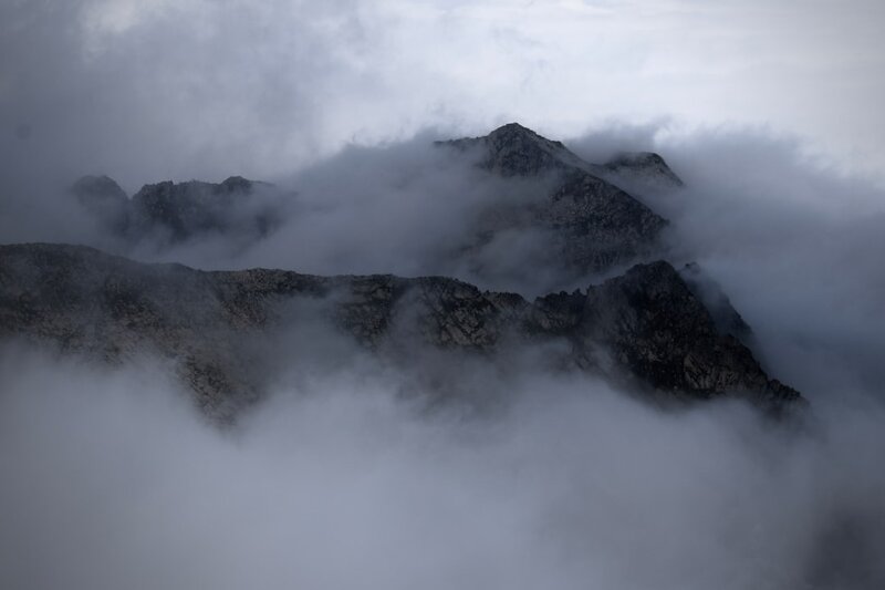 A mountain range almost entirely hidden by low cloud, the terrain visible but its shape unreadable