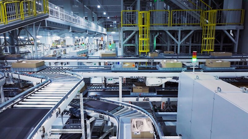 An automated parcel sorting line in a warehouse, boxes travelling along conveyor belts with nobody inspecting them