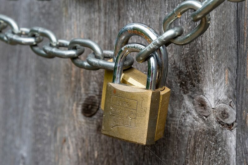 A brass padlock on a wooden fence