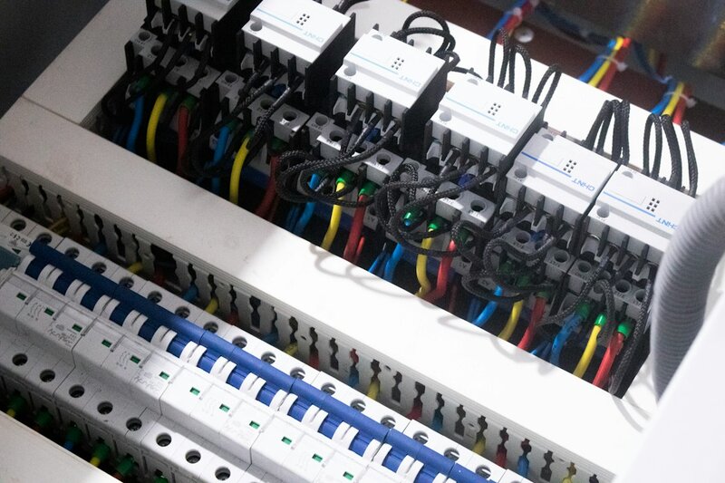 Rows of unlabelled circuit breakers and coloured wiring inside an open electrical panel