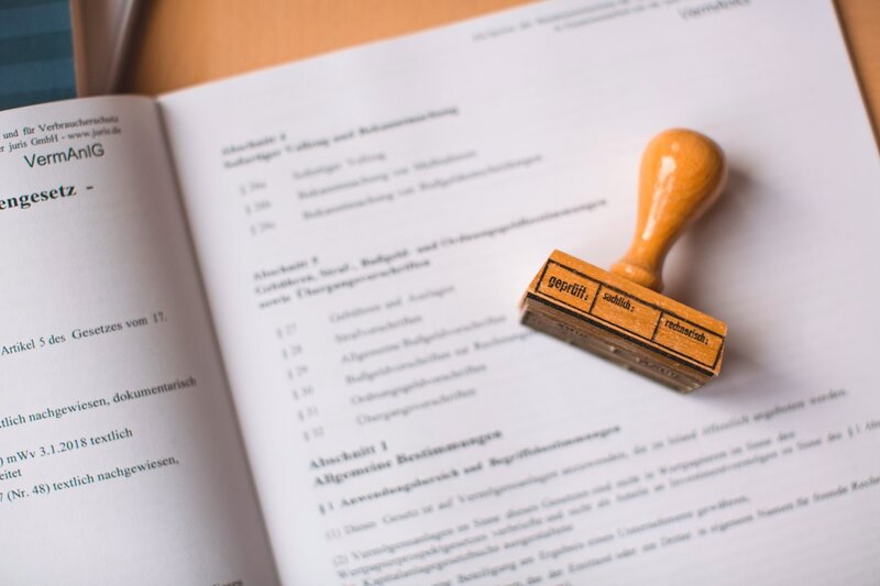 A wooden approval stamp resting on an open statute book