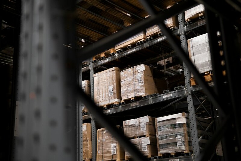 Pallets of boxes stacked on warehouse racking, seen through steel framing