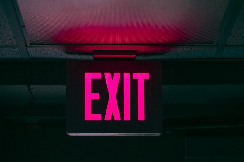 An illuminated red EXIT sign glowing in a darkened ceiling space